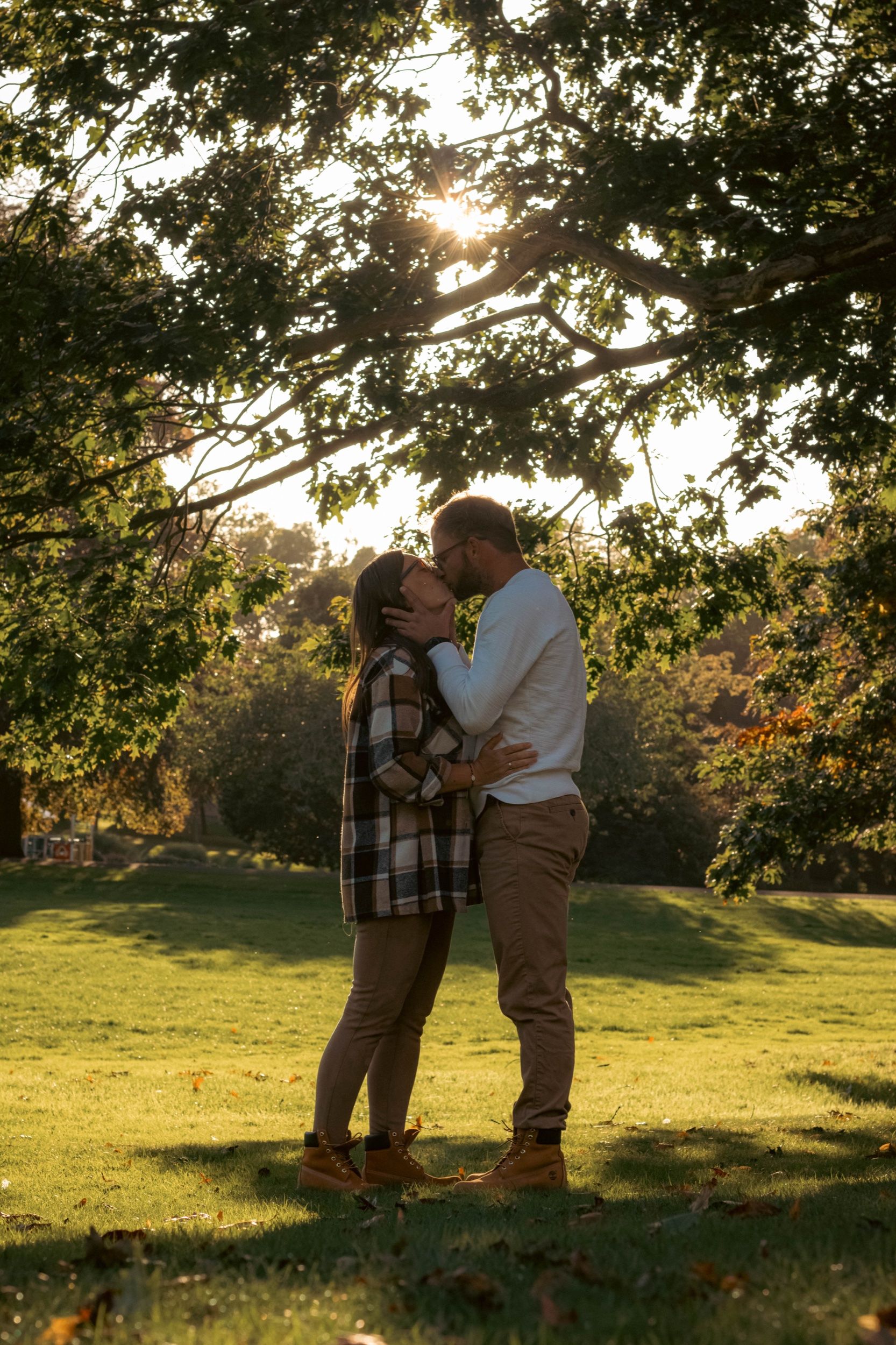 Couple kissing under a tree in low autumn sun